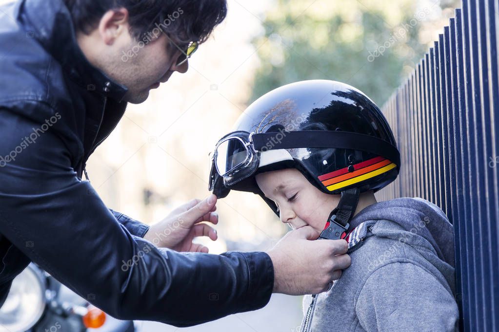 young loving dad fastens helmet to his son before travel