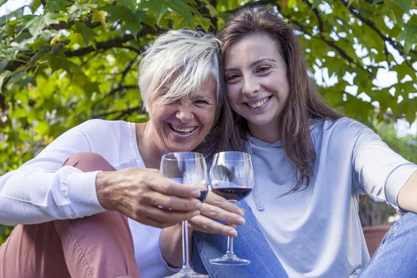 Matka i córka dorosły, degustacja wina, siedzi wielkie drzewo — Zdjęcie stockowe