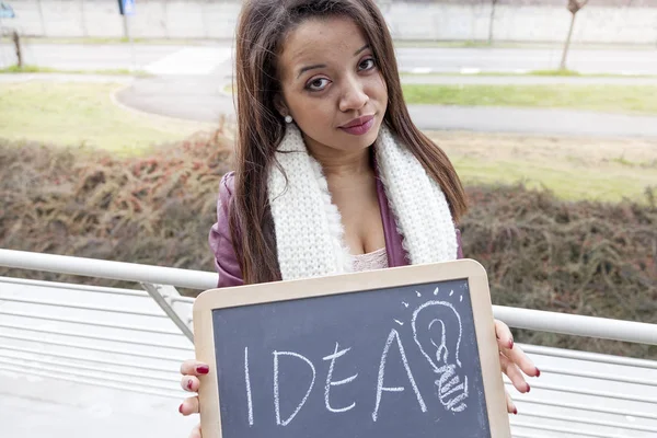 Young attractive businesswoman shows a blackboard marked with bu — Stock Photo, Image