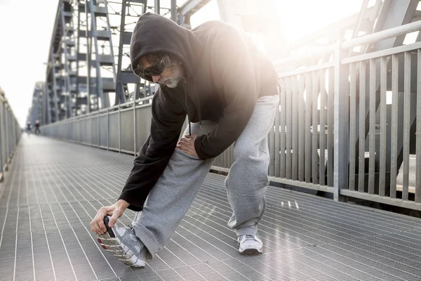 Atleta fazendo alongamento na ponte de metal. Estilo de vida saudável — Fotografia de Stock