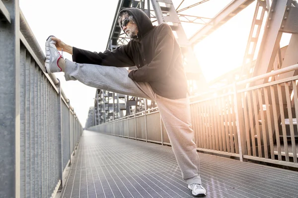 Atleta fazendo alongamento na ponte de metal. Estilo de vida saudável — Fotografia de Stock