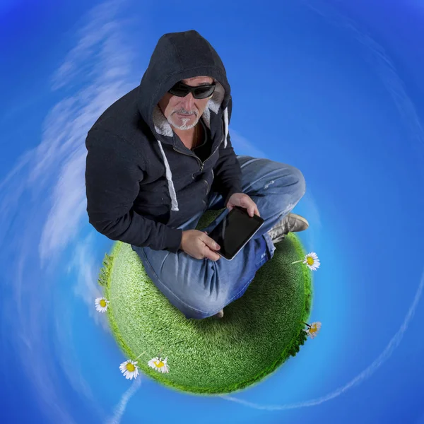 Hipster hombre con capucha sentado en un planeta de hierba controla lapto — Foto de Stock