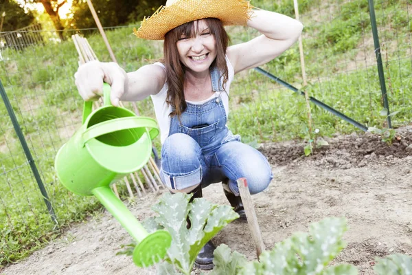 Mujer bonita regando plantas en el jardín — Foto de Stock