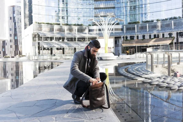 Jovem hipster empresário consulta seu laptop no coração da ci — Fotografia de Stock