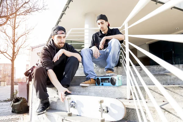 Два молодих скейтбордиста відпочивають на окраїнах сходів — стокове фото