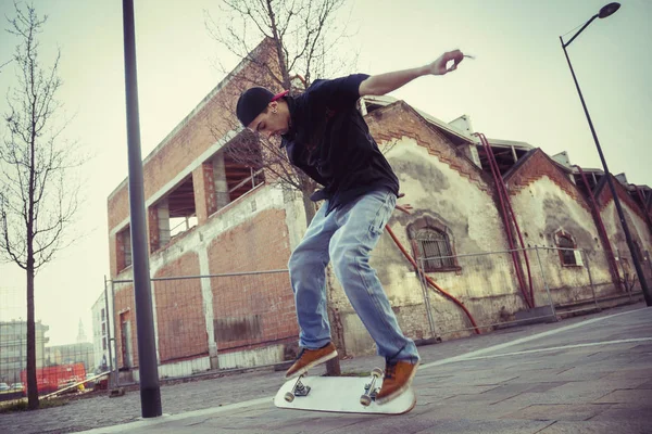 Giovane ragazzo che salta con skateboard in periferia strada — Foto Stock