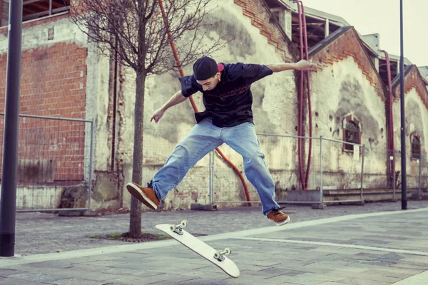 Giovane ragazzo che salta con skateboard in periferia strada — Foto Stock