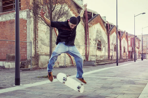 Молодий хлопчик стрибає зі скейтбордом на вулиці під спідницею — стокове фото