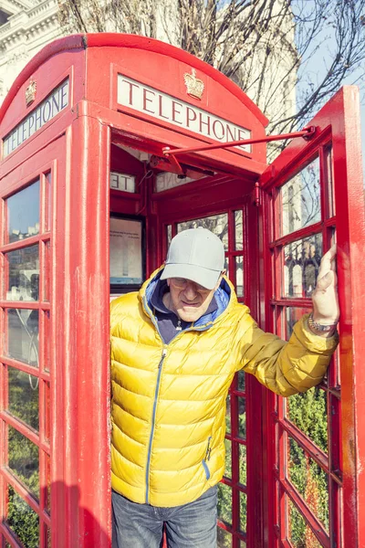 Mogen man går in i en röd telefonkiosk i London — Stockfoto