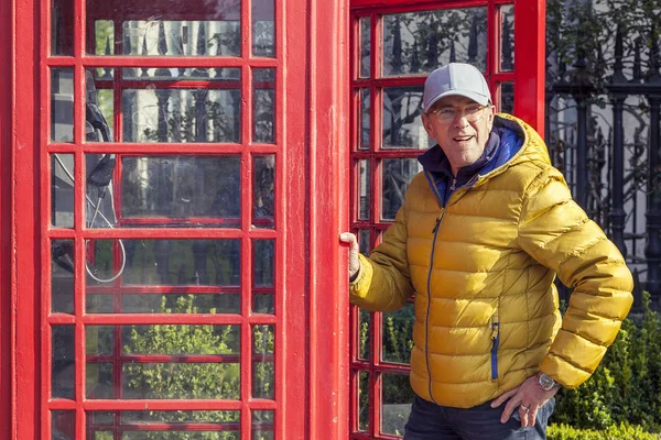 Volwassen man loopt in een rode telefooncel in Londen — Stockfoto
