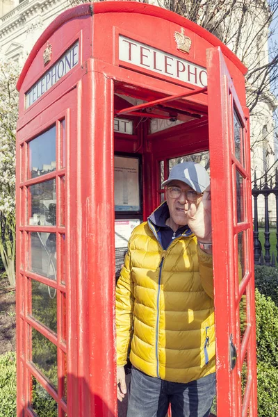 Mature man walks into a red telephone box in London — Stock Photo, Image