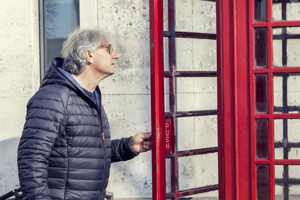 Volwassen man loopt in een rode telefooncel in Londen — Stockfoto