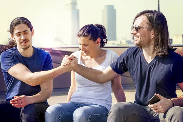 Grupp av tre unga vänner skakar hand på en london-terrass — Stockfoto
