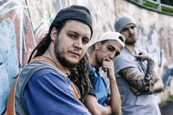 three rap singers in a subway with graffiti in the background