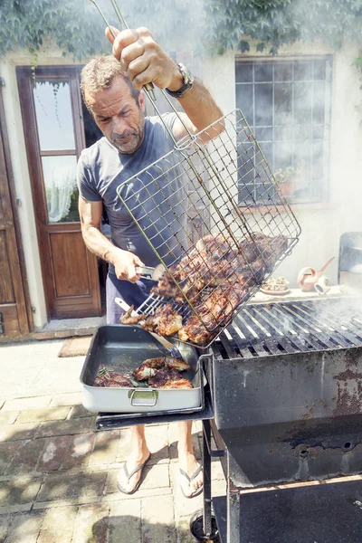 Hombre guapo preparando carne a la parrilla para amigos al aire libre — Foto de Stock