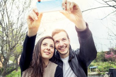 nice couple boyfriends takes a selfie relaxing in the park outdo clipart