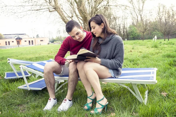 Ωραίο ζευγάρι Χαλαρώστε στην ξαπλώστρα ανάγνωση βιβλίων και tablet — Φωτογραφία Αρχείου