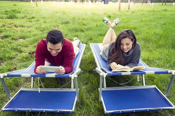 Hezký pár odpočívat na lehátku, čtení knih a tablety — Stock fotografie