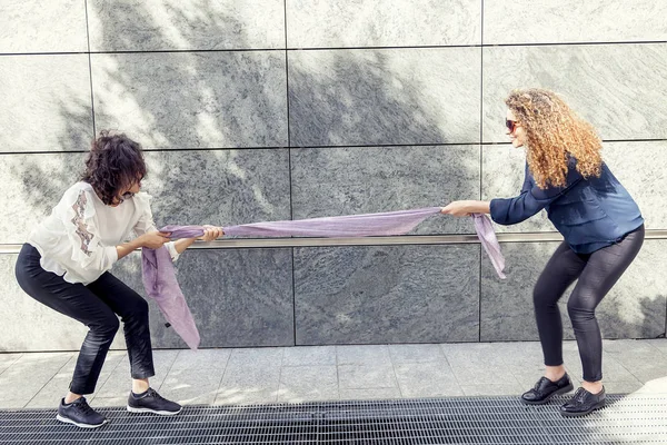 Due belle ragazze improvvisano un tiro alla fune con una sciarpa — Foto Stock