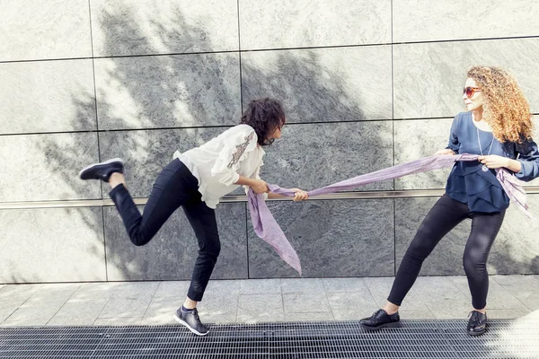 Dwa ładne dziewczyny improwizować przeciąganie liny z szalikiem. — Zdjęcie stockowe