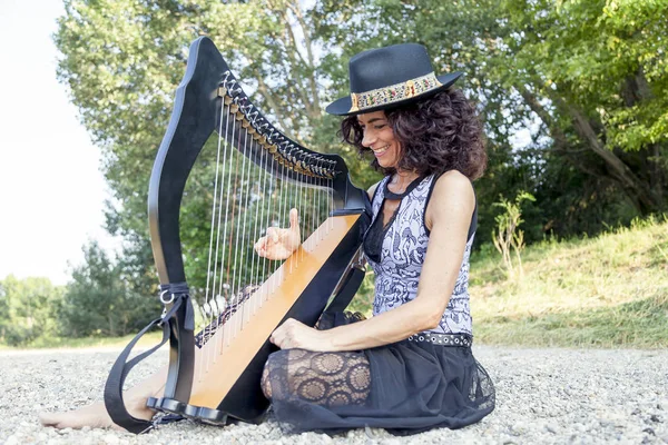 Vackra lockiga hår kvinna som spelar harpa — Stockfoto
