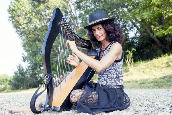 Vackra lockiga hår kvinna som spelar harpa — Stockfoto
