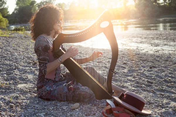 Hermosa mujer pelo rizado tocando el arpa — Foto de Stock