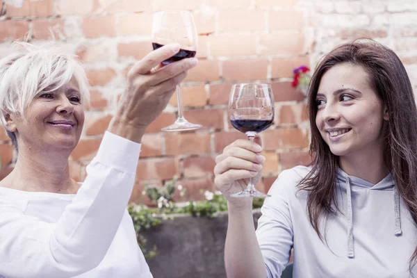 Mãe e filha adulta degustação de vinho sentado ao ar livre — Fotografia de Stock