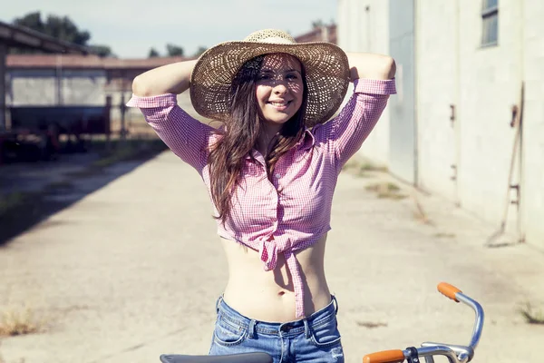 Bonita jovem mulher de bicicleta em uma estrada rural — Fotografia de Stock