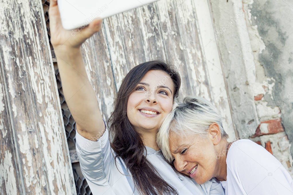 mother and adult daughter take a selfie outdoors