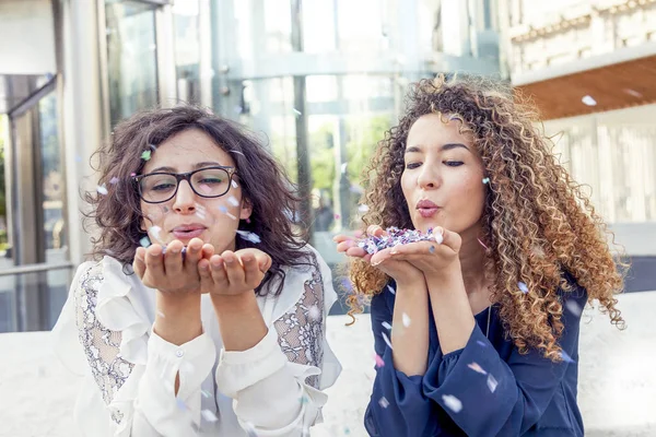 Due ragazze soffiando alcuni coriandoli pezzo — Foto Stock