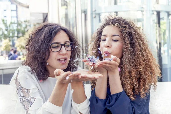 Két lány fúj néhány konfetti darab — Stock Fotó