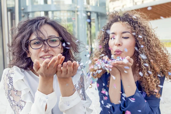 Due ragazze soffiando alcuni coriandoli pezzo — Foto Stock