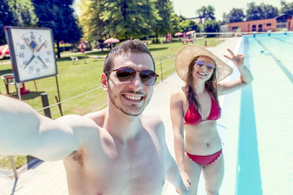 Joven pareja amorosa al lado de la piscina toma una selfie — Foto de Stock