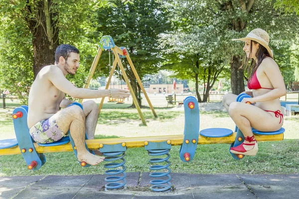 Un par de adultos jóvenes se divierten en un balancín — Foto de Stock