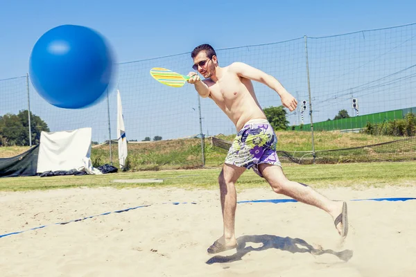 Jeune homme adulte joue au tennis sur la plage — Photo