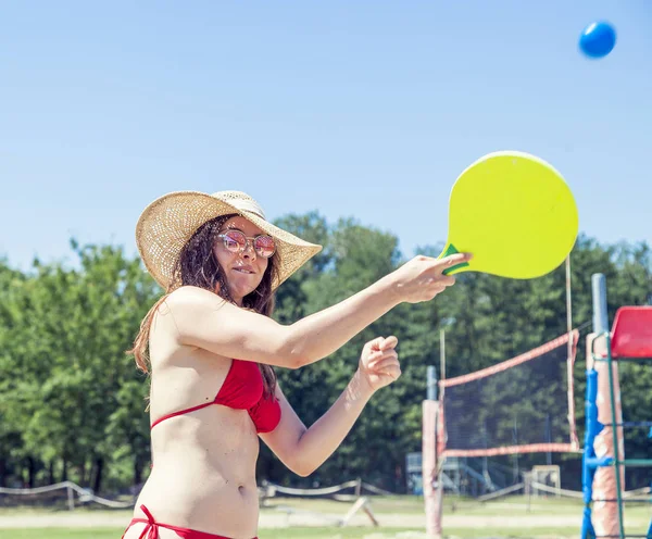 Jovem mulher adulta jogando tênis na praia — Fotografia de Stock