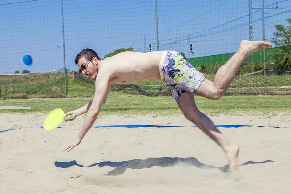 Jeune homme adulte joue au tennis sur la plage — Photo