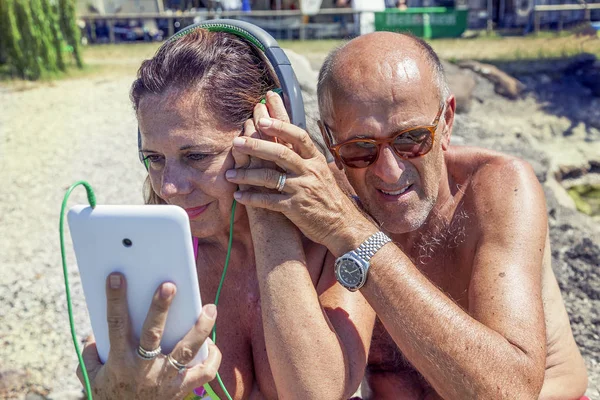 Moderna pareja madura escuchando música con auriculares — Foto de Stock