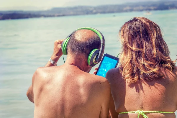 Moderna pareja madura escuchando música con auriculares — Foto de Stock