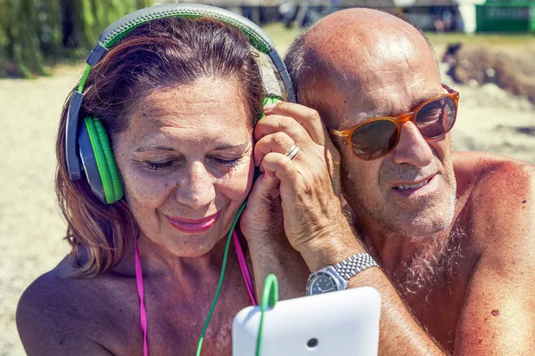 Moderna pareja madura escuchando música con auriculares — Foto de Stock