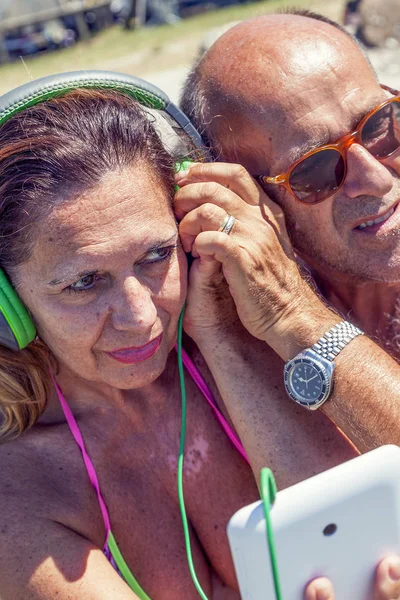 Moderna pareja madura escuchando música con auriculares — Foto de Stock