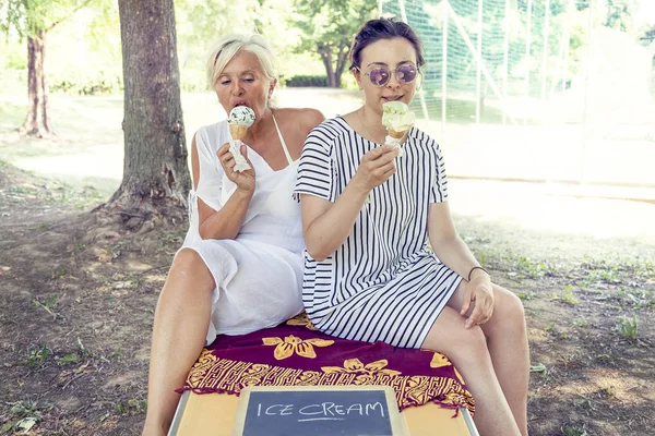 Mãe moderna e jovem filha comendo sorvete — Fotografia de Stock