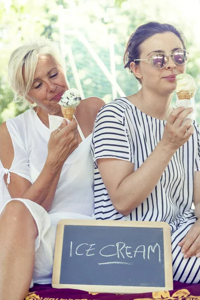 Modern mom and young daughter eating ice cream — Stock Photo, Image