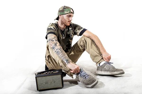 Sentado tatuado rap cantante posando en estudio — Foto de Stock