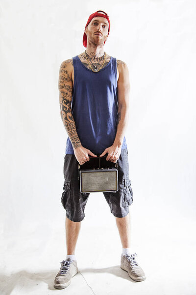 tattooed rap singer posing in studio with an amplified radio