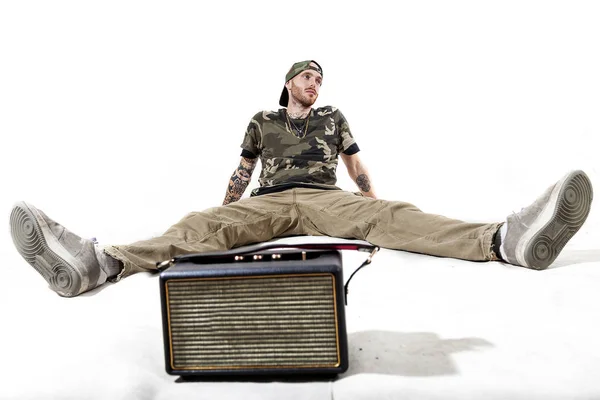 Сидящий татуированный рэп-певец позирует в студии — стоковое фото
