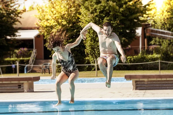 Joven pareja de amantes saltando en la piscina — Foto de Stock