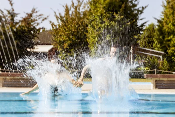 Jeune couple d'amoureux sautant dans la piscine — Photo