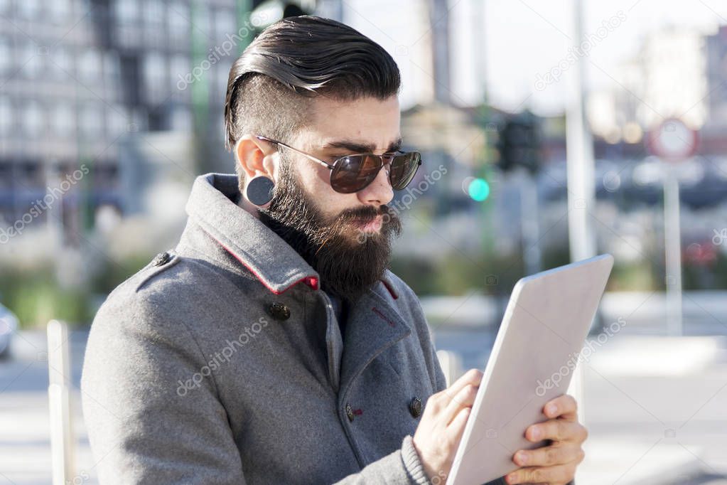 young hipster businessman consults his laptop in the heart of ci